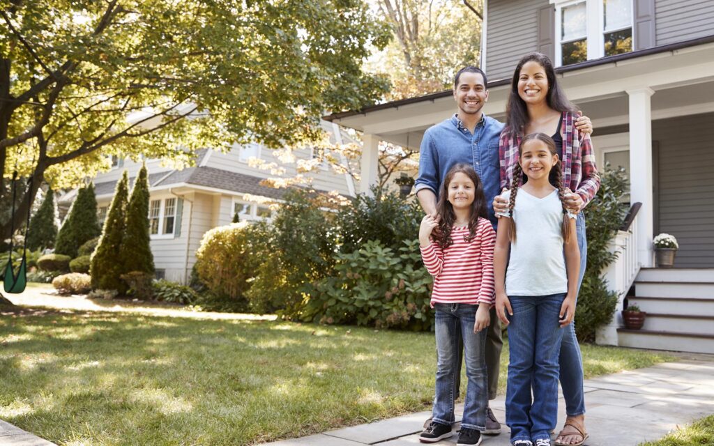 Homepage - Family Standing in Front of Their Home on a Quiet Suburban Street